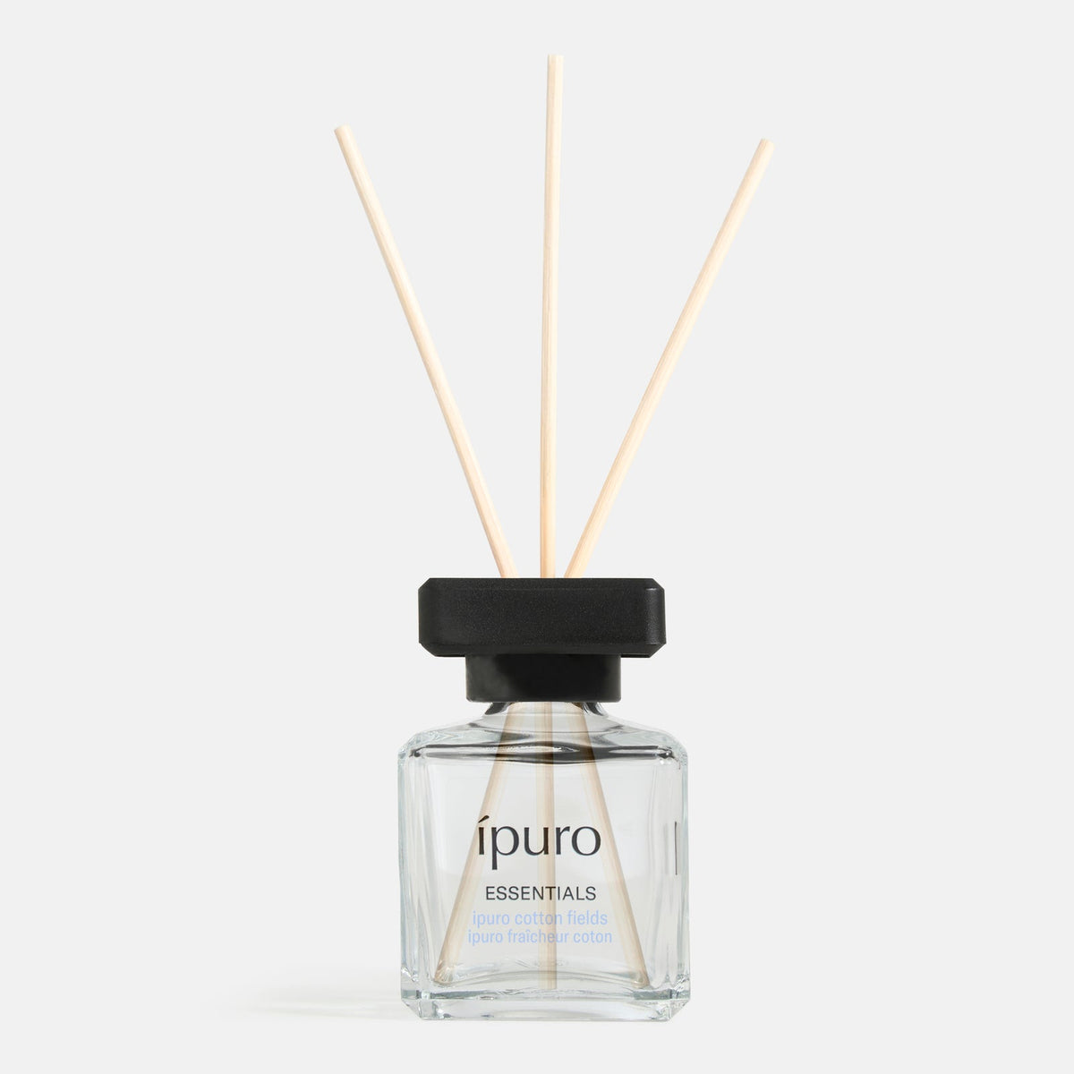 Eine Glasflasche ipuro Raumduft Baumwollfelder Schilf Diffusor mit einer schwarzen Kappe und drei Holzstäbchen, gefüllt mit einem klaren Duft, ist vor einem weißen Hintergrund angezeigt, um Ihr Raumklima zu verbessern.