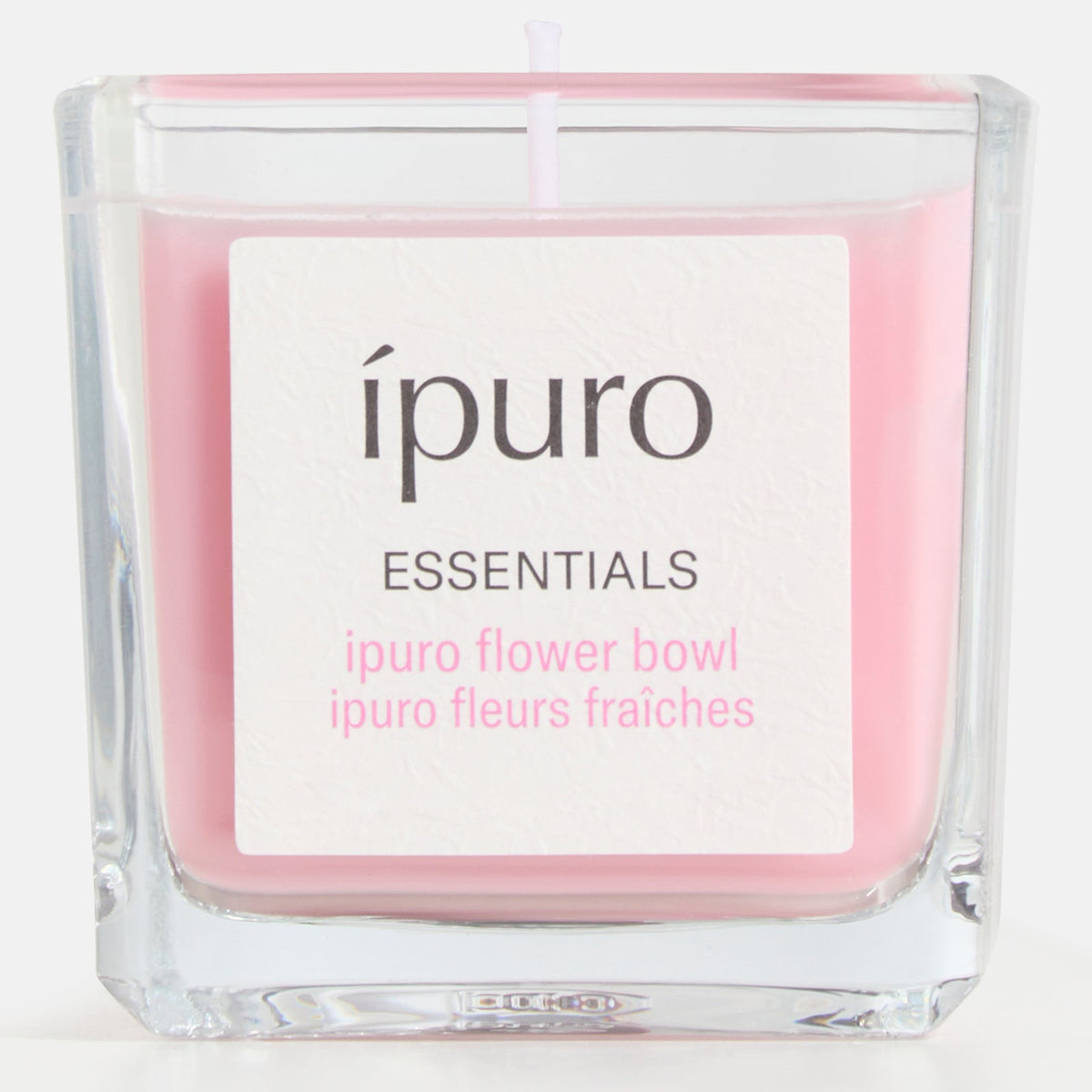 Die Duftkerze ipuro flower bowl von ipuro ist eine rosafarbene Kerze in einem klaren, quadratischen Glasbehälter, die ein blumiges, sommerliches Flair und belebende Frische in jeden Raum bringt.