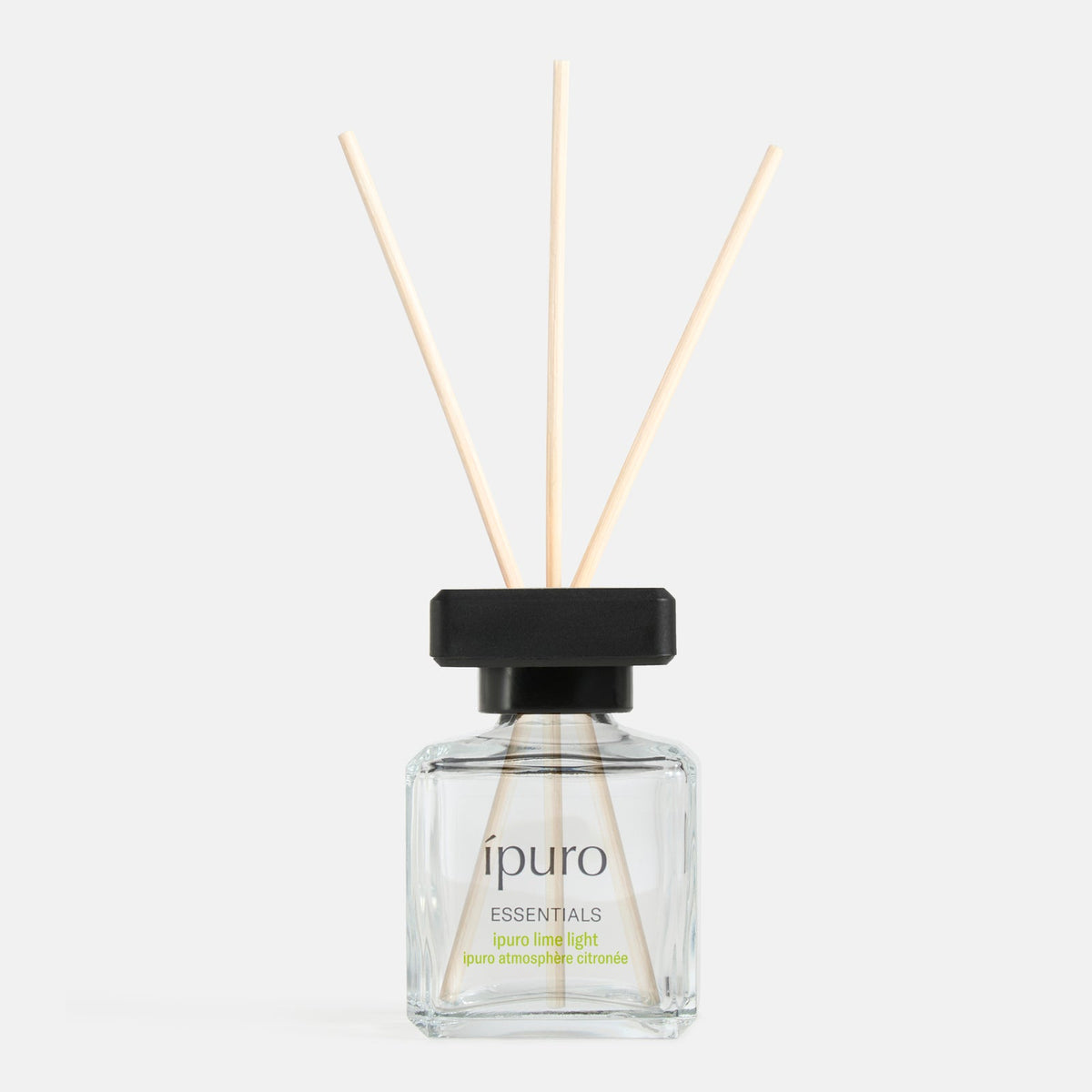 Ein klarer Glasrohrdiffusor mit schwarzer Kappe und drei Holzstäbchen mit der Aufschrift ipuro lime light von ipuro verströmt frische und blumige Noten von Zitronengras vor einem schlichten weißen Hintergrund.