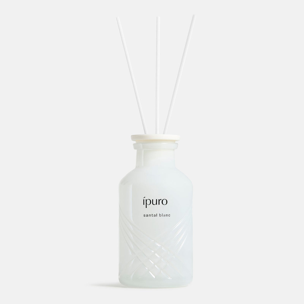 Der mattweiße ipuro santal blanc Raumduft Diffusor von ipuro mit drei weißen Schilfstäbchen verbreitet Düfte von Sandelholz und weißer Orchidee vor einem schlichten, hellen Hintergrund.