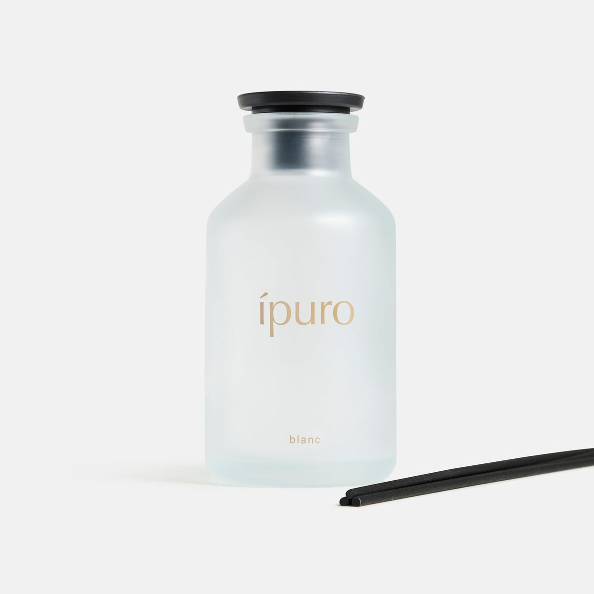 Ein Milchglasflakon mit der Aufschrift ipuro und dem Schriftzug "Raumduft CLASSIC ipuro blanc", mit Noten von Sandelholz und Geranien, einer schwarzen Kappe und zwei schwarzen Diffusorstäbchen auf weißem Hintergrund.