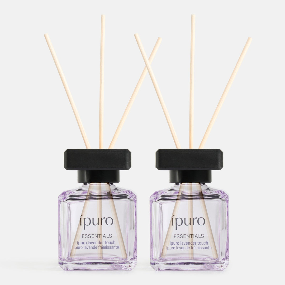 Das Raumduft-Set ipuro lavender touch von ipuro besteht aus zwei klaren, quadratischen Flaschen mit schwarzem Deckel, die jeweils mit hellvioletter Flüssigkeit gefüllt sind, und drei Schilfrohrstäbchen, die einen sanften Lavendelduft mit einem Hauch von Minze in Ihren Raum bringen.