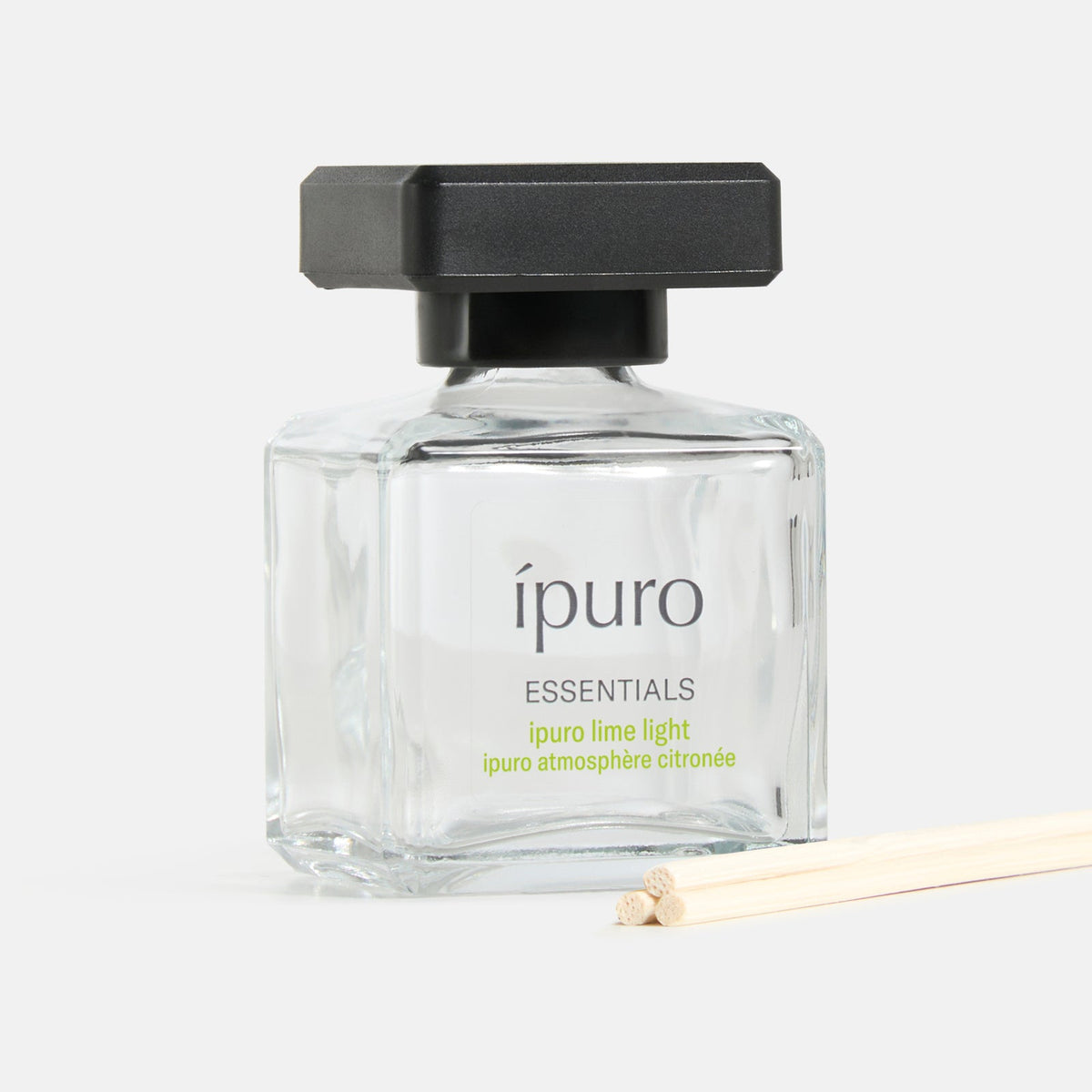 Ein klarer Glasflakon mit der Aufschrift Raumduft ipuro lime light von ipuro, mit einer schwarzen quadratischen Kappe und drei hölzernen Diffusorstäben, suggeriert Frische und einen blumigen Duft vor einem schlichten weißen Hintergrund.