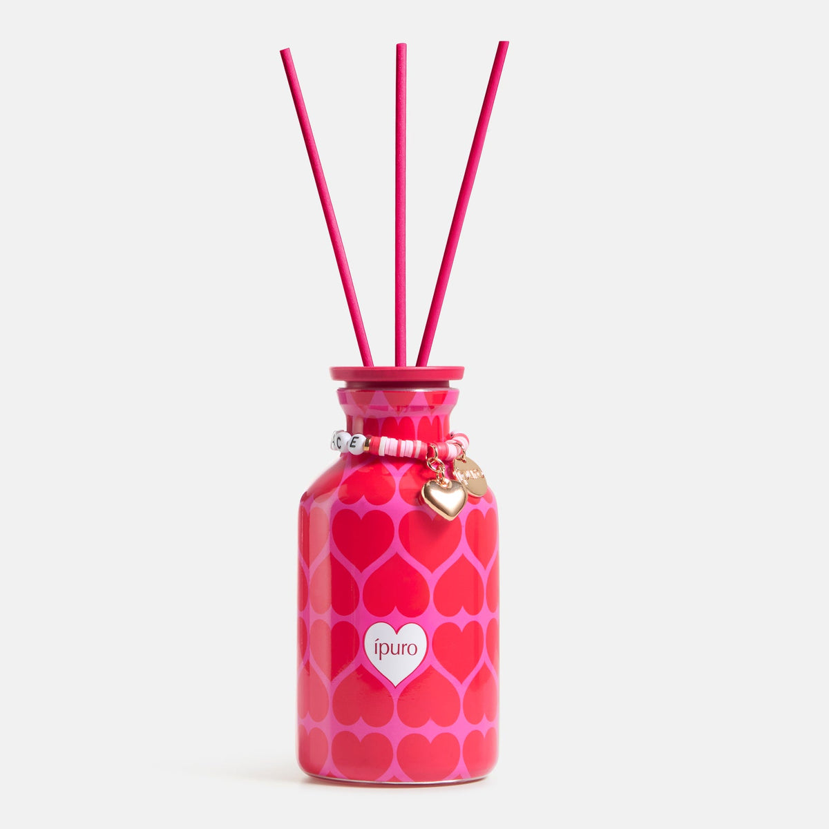 Der ipuro Raumduft love's embrace 240ml besteht aus einer rosafarbenen Diffusorflasche mit Herzmotiven, drei Schilfrohrstäbchen und einem Armband mit einem goldenen Herz und weißen Perlen, die Ihrer Einrichtung einen herrlichen Orangen-Mandarinen-Mango-Duft verleihen.
